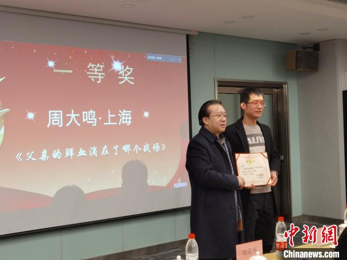 圖為作家、西北師范大學(xué)新聞與傳媒學(xué)院院長(zhǎng)徐兆壽頒發(fā)一等獎(jiǎng)證書(shū)，代領(lǐng)獎(jiǎng)?wù)呱吓_(tái)領(lǐng)獎(jiǎng)?！钅?攝