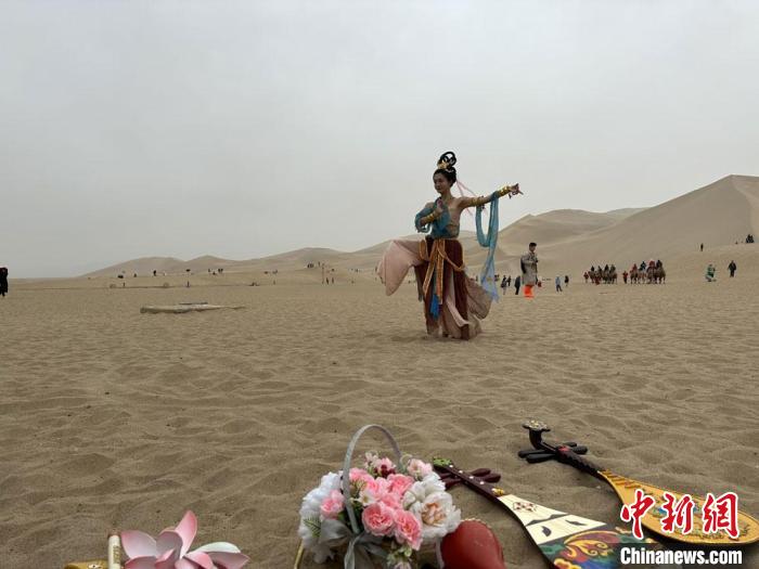 圖為2023年4月底，敦煌大漠“逐舞者”奧楠在鳴沙山月牙泉景區(qū)視頻直播敦煌舞。　馮志軍 攝